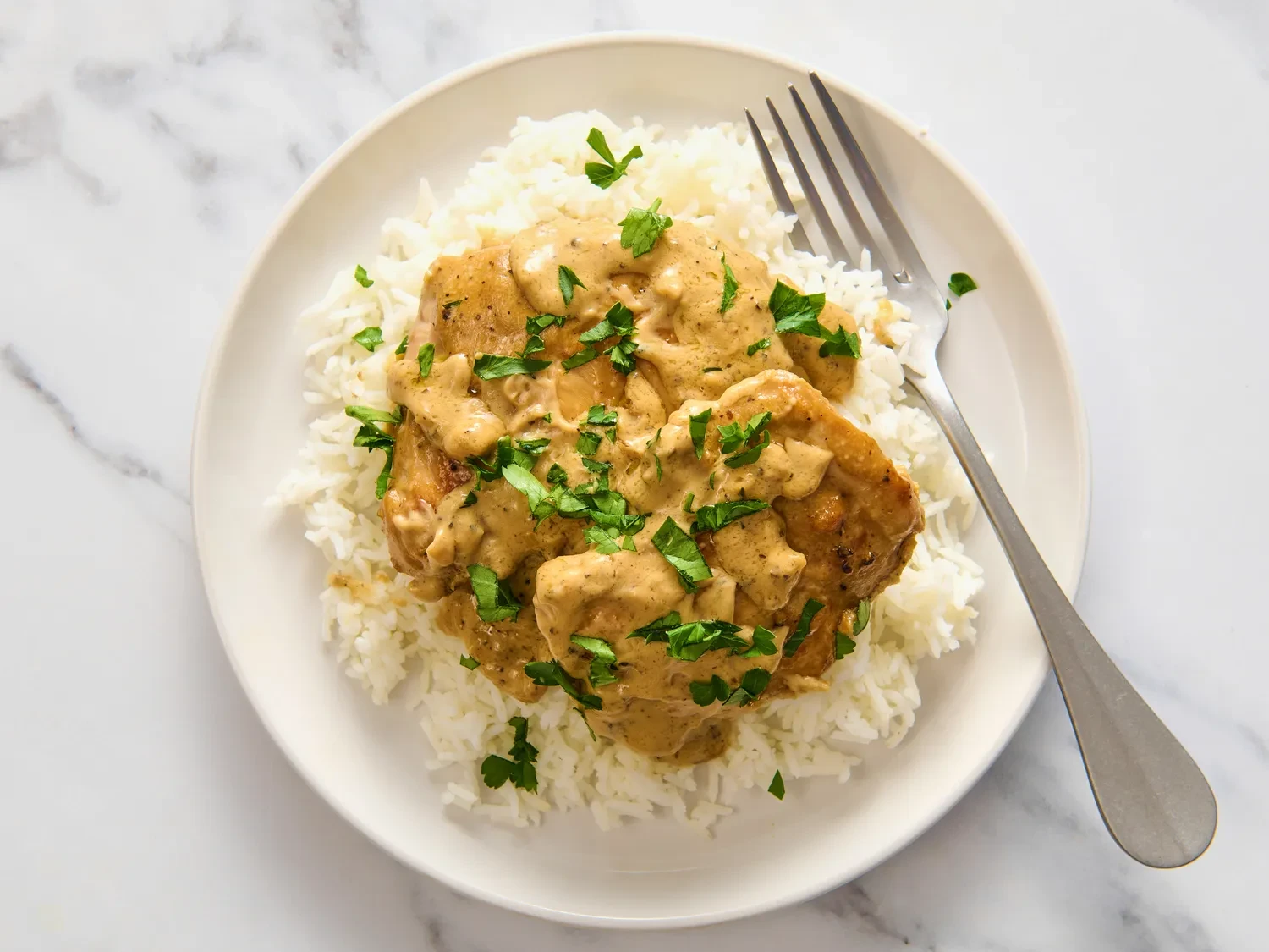 Chicken au poivre in creamy peppercorn sauce over white rice with fresh herbs